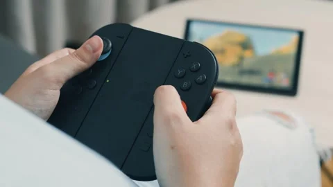 Grasping nintendo switch 2 controller, blurred racing game screen behind, Stock Footage 312441539