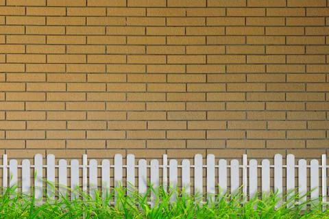 Grass and bricks wall and white fence Stock Photos