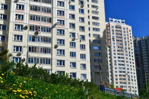 Grass and dandelions in front of a multi-storey building. Russia Stock Photos