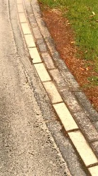 Grass borders pavement creating contrast between natural growth dirt patch Stock Photos
