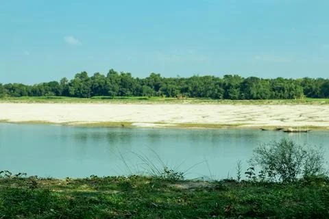 Grass on both sides of a small river and with on a white and blue sky Stock Photos