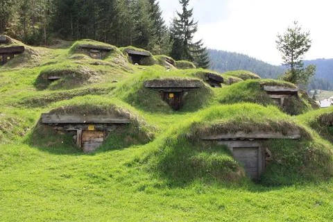 Grass-covered underground cellars built into a hillside in a rural mountain Stock Photos