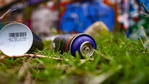 Grass covers scattered spray cans on the ground Stock Photos