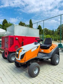 Grass cutting machine parked next to a red generator at an outdoor venue in.. Stock Photos