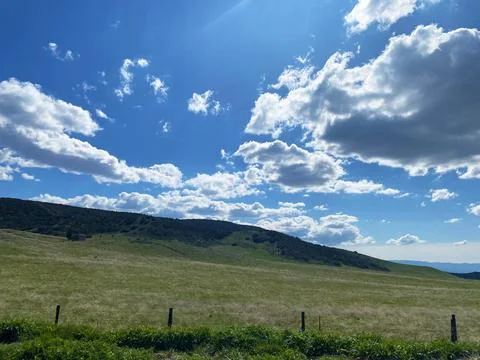 Grass field, blue sky with some clouds, hills Stock Photos