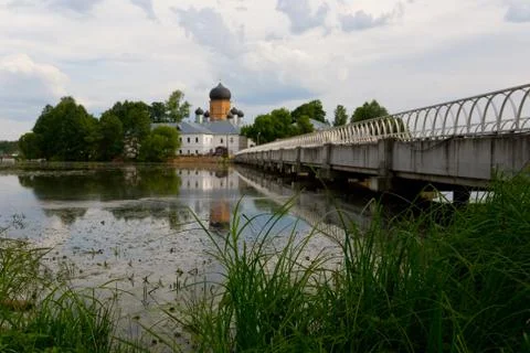 The grass grows next to the pond on the background of the church. Stock Photos