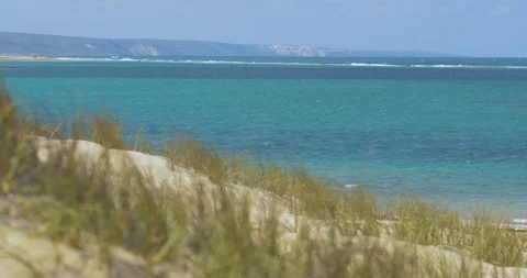Grass on sand dune looking out across the turquoise water Stock Footage 88267571