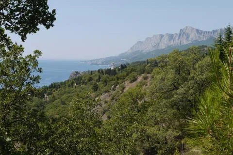 Grass slopes on the background of high steep cliffs and the boundless black s Stock Photos