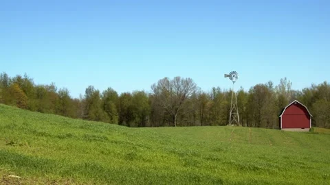 Grass waves gently in the breeze on a hill by a barn and windmill. 4k60p Stock Footage 132433945