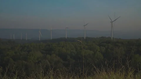 Grass on windy and blurred wind turbine on blue sky background Stock Footage 258984222