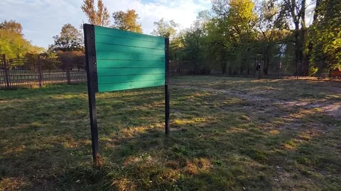 Grassy area within a dog park featuring a prominent teal sign, supported by Stock Footage 319455091