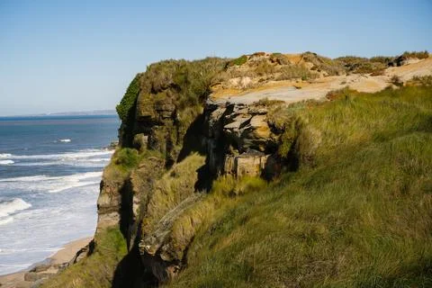 Grassy cliff edge above Atlantic Ocean shoreline Stock Photos