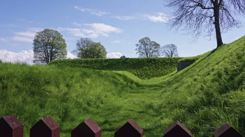 Grassy Fortification with Bench, Trees and Red Fence Detail Stock Footage 309454990