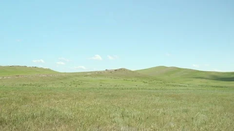Grassy hillside with a car driving in the background on a sunny day. Stock Footage 258113637