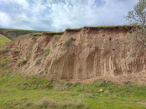 Grassy hillside, cut, soil eroded and landslide, clay, sand taken Stock Photos