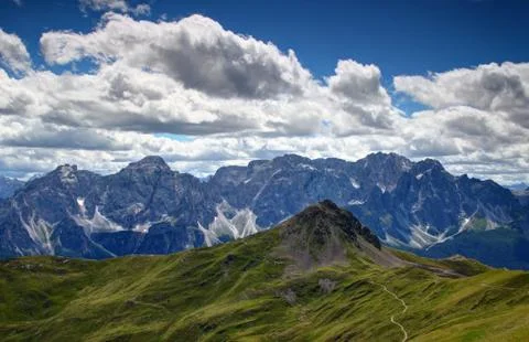 Grassy slopes of Carnic Alps with cliffs of Sexten Dolomites Stock Photos