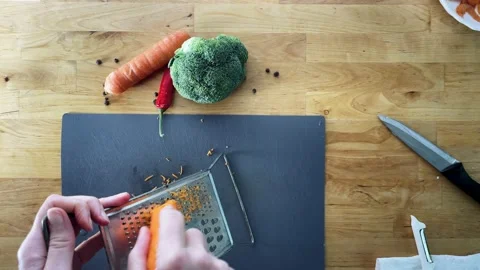 Grate the carrots on the grater top view wooden countertop Stock Footage 228433071