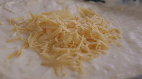 Grated cheddar cheese falling down on pasta and woman stirring 스톡 동영상 255029657