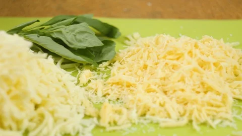 Grated cheese and basil lie on a green cutting board Stock Footage 105898474