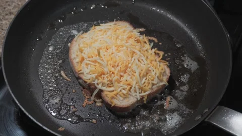 Grated cheese melting on bread in pan Stock Footage 336688694