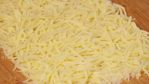 Grated cheese spreading smoothly across wooden cutting board Stock Footage 313913152