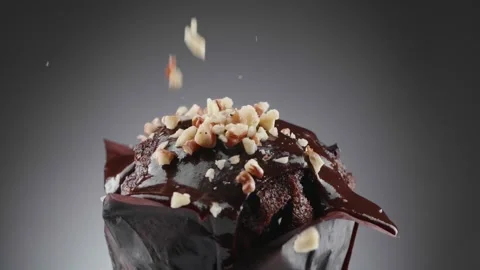 The grated nuts are poured on top of the chocolate covered muffin. Stock Footage 150093055