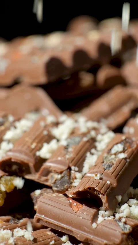 Grated nuts are sprinkled on nutty milk chocolate, healthy sweets. Vertical slow Stock Footage 293297767