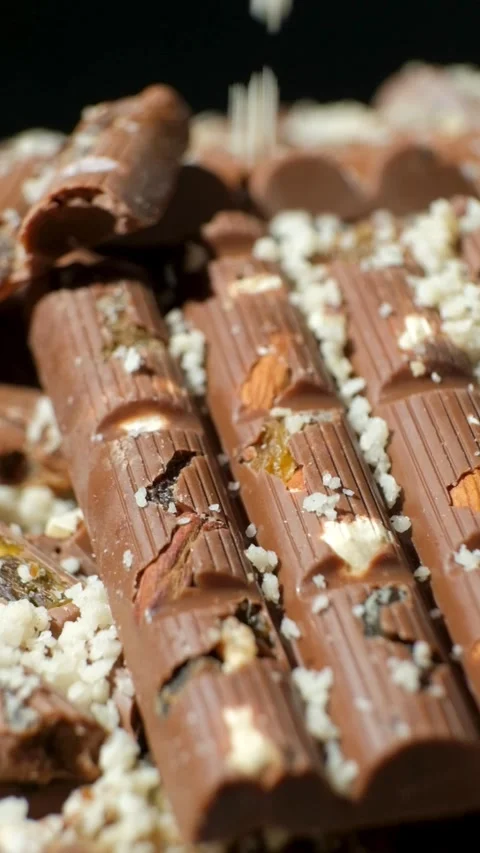Grated nuts are sprinkled on nutty milk chocolate, healthy sweets. Vertical slow Stock Footage 293463044