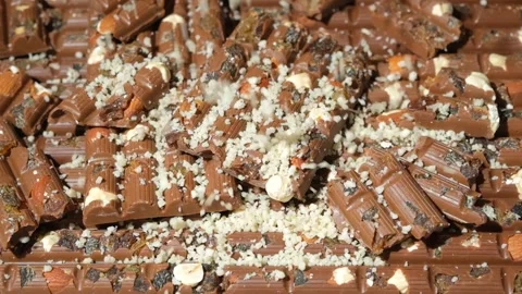 Grated nuts are sprinkled on nutty milk chocolate, healthy sweets Stock Footage 293463753