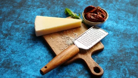 Grated parmesan cheese and metal classic grater placed on wooden cutting board Stock Footage 97787553