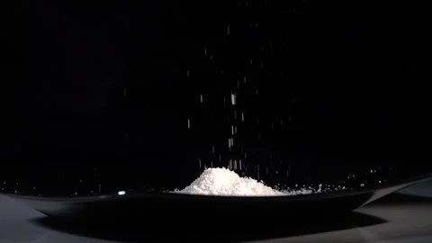 Grated Parmesan cheese falls in slow motion onto a black kitchen plate Stock-Footage 143163483