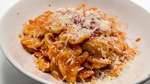 Grated Parmesan cheese sprinkled over orecchiette pasta with tomato sauce Stock Footage 313946067
