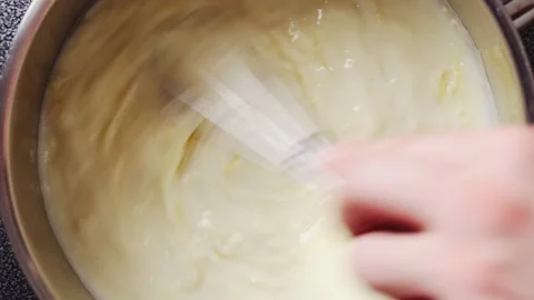 Grated parmesan goes into cheese sauce, whisk mixing in close up. Stock Footage 341950964