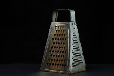 Grater on a dark background. Old rusty grater on a black background. Stock Photos