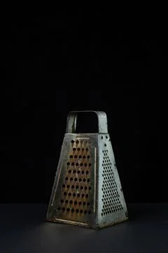Grater on a dark background. Old rusty grater on a black background. Stock Photos