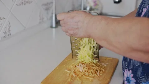 Grating apple on a cutting board with selective focus. Preparation for making Stock Footage 221015444