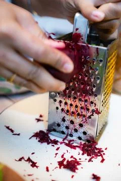 Grating beetroot with a steel grater in a ceramic plate. Foto stock