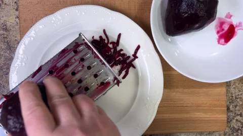 Grating boiled beets on grater on white plate background.	 Stock-Footage 302277438