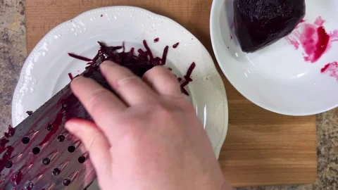 	Grating boiled beets on grater on white plate background. Video stock 302278284