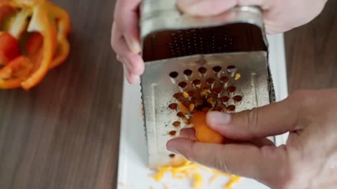 Grating Carrot Over White Board, Caucasian Hands Rub Orange Vegetable Against Stock Footage 323941371