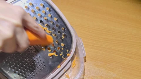 Grating carrots with a kitchen tool on a wooden table Stock Footage 325794539