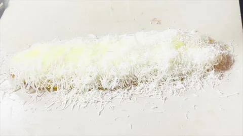 Grating cheddar cheese on top of fried bananas for traditional snack Stock Footage 333637731