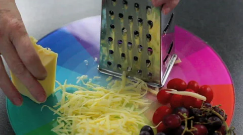Grating cheese against colorful choping board Stockbeeldmateriaal 42179970
