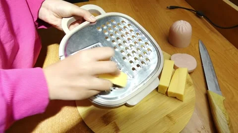 Grating cheese and preparing food on a wooden board in a kitchen setting Stock Footage 328416667