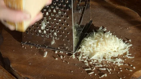 Grating a cheese on grater close up illuminated by sun Stock Footage 95033691