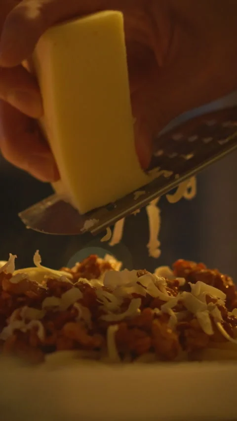 Grating cheese over a delicious plate of food in a cozy evening kitchen Stock Footage 331592129
