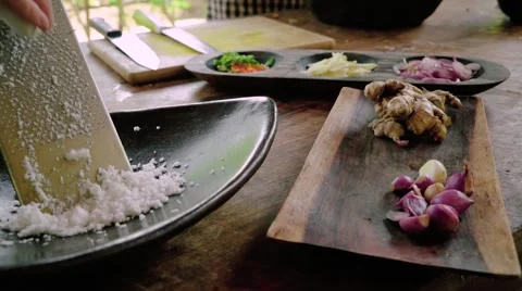 Grating coconut on kitchen table, other vegetables around it Video stock 57523384