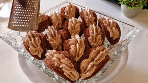 Grating dark chocolate over creamy mousse cakes for a professional bakery finish Stock Footage 326633565