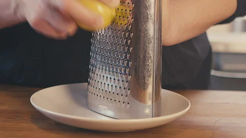 Grating fresh lemon peel, lemon skin with metal grater, on a white plate, on a Stock Footage 273499791