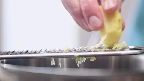 Grating ginger root with a grater in the kitchen. Stock Footage 153457422